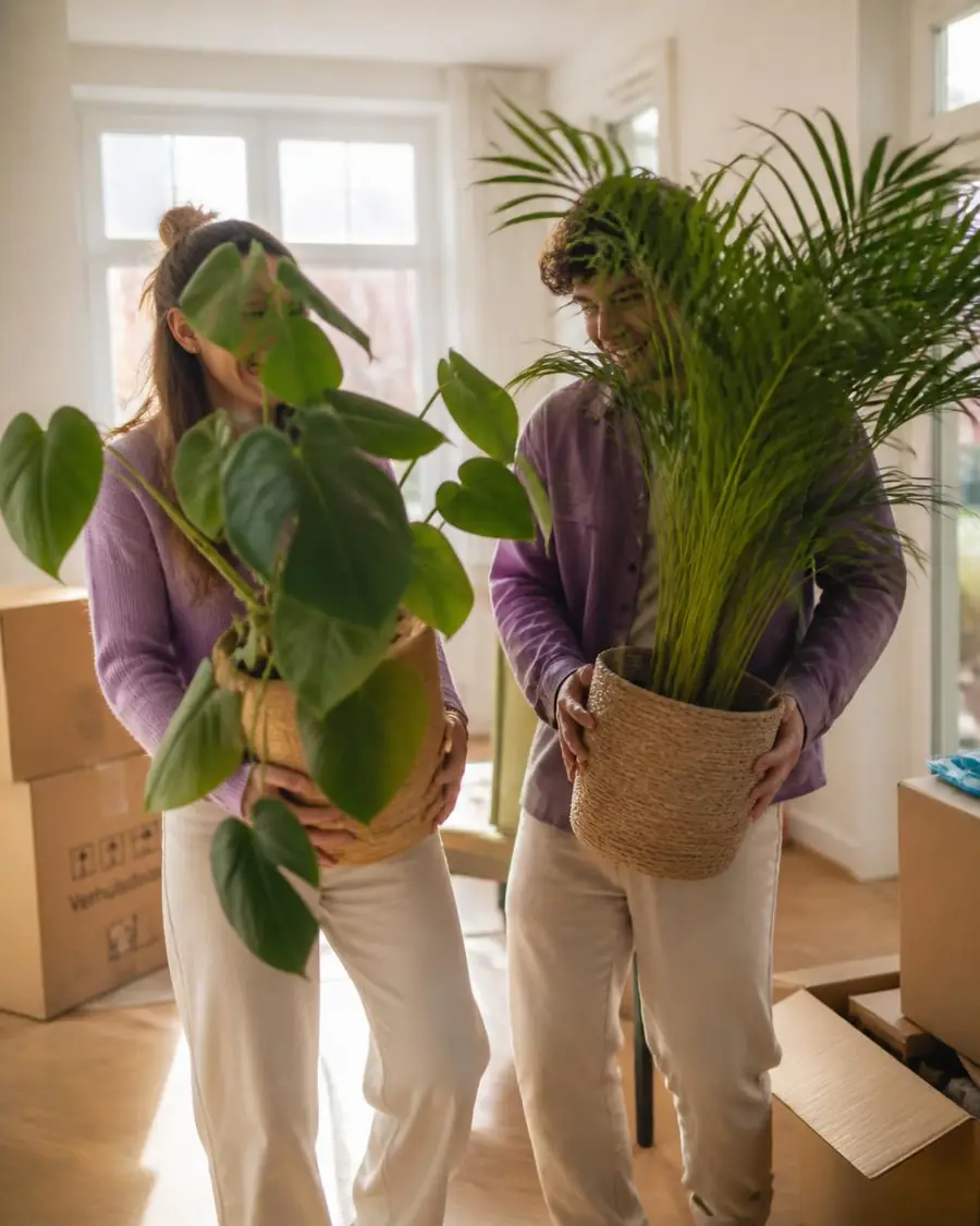 Jong stel verhuist naar hun nieuwe woning met planten in hun handen