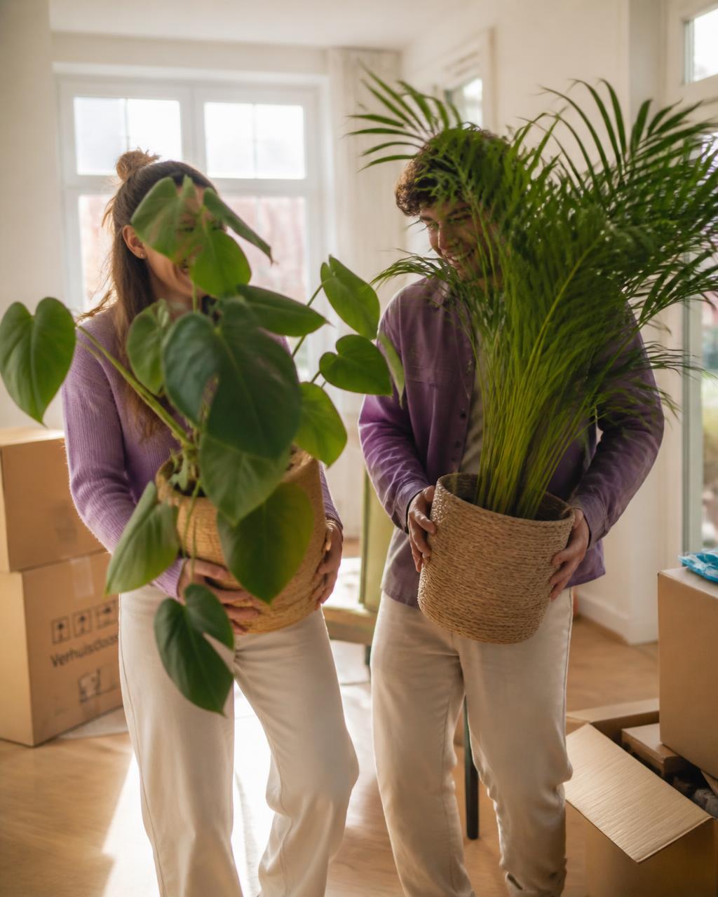 Jong stel verhuist naar hun nieuwe woning met planten in hun handen